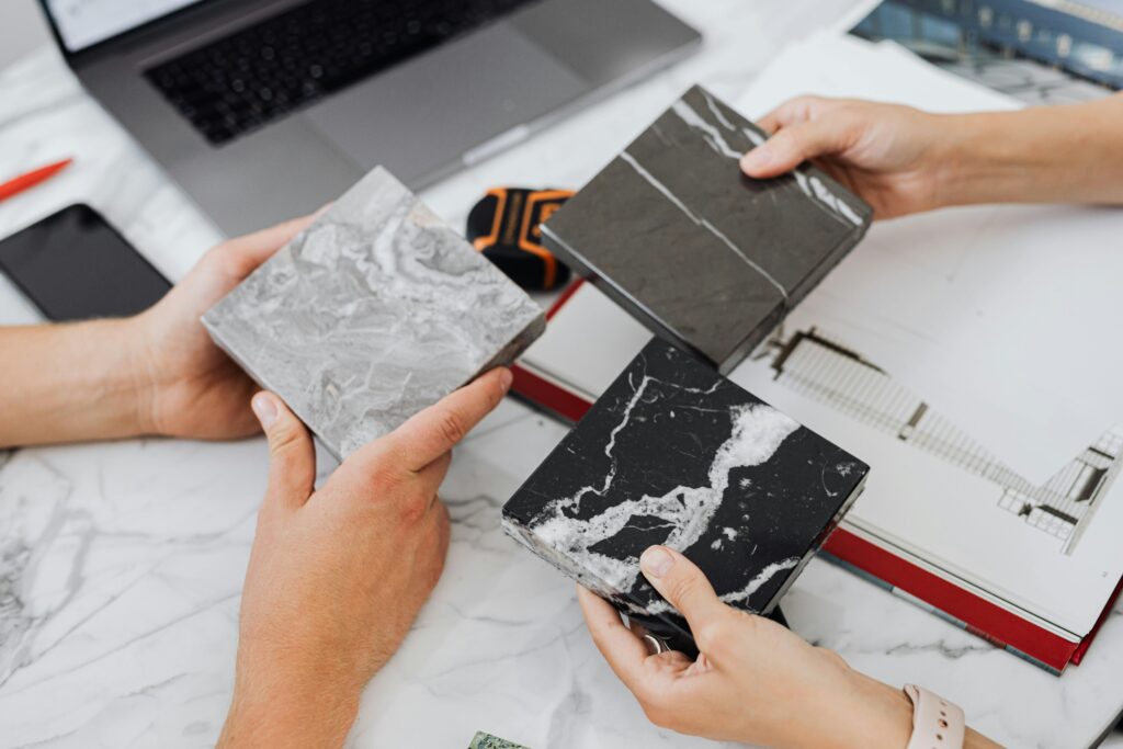 pexels-photo-4977410-4977410 Two architects selecting marble tile samples on a desk in an office setting.